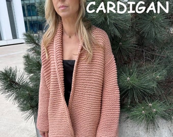 May include: A soft pink knitted cardigan with a long, open front and long sleeves. The cardigan is made of a chunky yarn and has a relaxed fit.