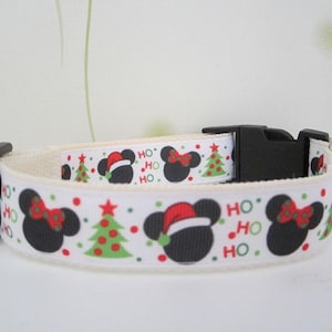 May include: White dog collar with a festive Christmas design. The collar features black Mickey Mouse silhouettes with red bows and Santa hats, green Christmas trees, and the words "HO HO HO" in red and green.