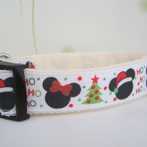 May include: White dog collar with a black plastic buckle. The collar features a repeating pattern of black mouse silhouettes with red bows and Santa hats, green Christmas trees, and the words "HO HO" in green and red.