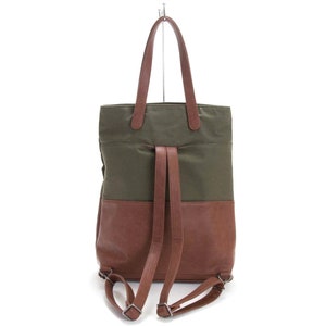 May include: A green and brown canvas and leather tote bag with adjustable straps that can be worn as a backpack.