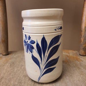 May include: A white ceramic mug with a black handle and the text "But First, Coffee" in a black, handwritten-style font. The mug is on a white surface.
