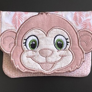 May include: A pink and white fabric wallet with a monkey face applique. The monkey has large green eyes, a smiling mouth, and pink ears. The background fabric has a pink leaf pattern.