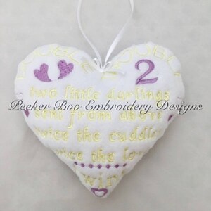 May include: White heart-shaped pillow with yellow and purple embroidery. The pillow reads "Two little darlings sent from above twice the cuddles twice the love twins".