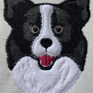 Könnte beinhalten: Gestickter Kopf eines schwarzen und weißen Border Collies mit herausgestreckter roter Zunge. Der Hund lächelt mit offenem Maul.