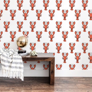 May include: A white wall with a repeating pattern of orange lobsters. A wooden bench with a white and black striped throw blanket sits in front of the wall. A gold globe sits on the bench.