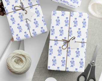 May include: Three white gift boxes with blue and white patterned wrapping paper featuring a repeating design of toy soldiers. The boxes are tied with brown twine and have white gift tags attached.