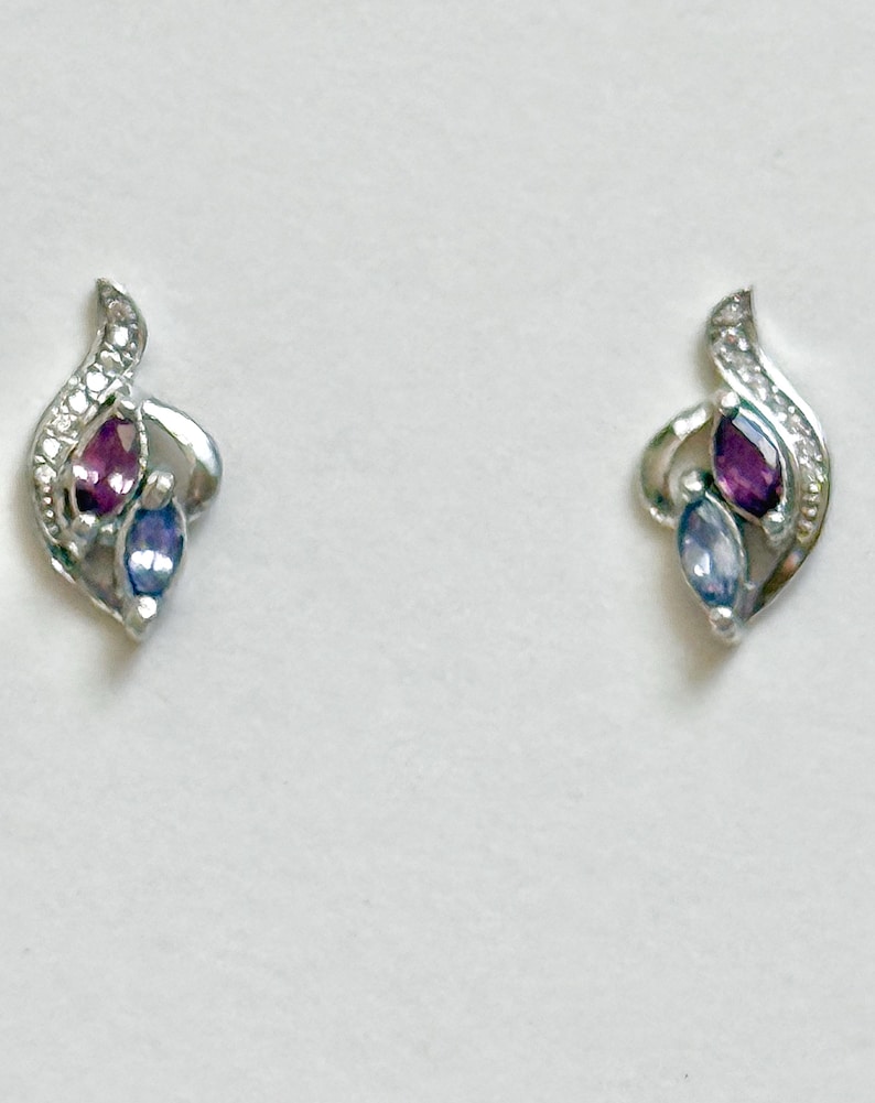 Peut inclure: Une paire de boucles d'oreilles &agrave; tige argent&eacute;es pr&eacute;sentant un design incurv&eacute; en forme de flamme. Chaque boucle est orn&eacute;e d'une pierre pr&eacute;cieuse violette taille marquise et d'une pierre bleu clair taille marquise, avec des &eacute;clats clairs.