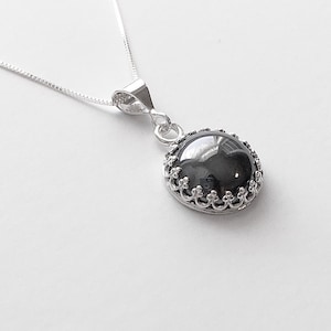 May include: A silver necklace with a black gemstone pendant. The pendant has a decorative silver border.