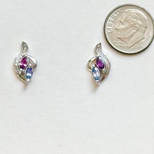 Peut inclure: Une paire de boucles d'oreilles argent&eacute;es au design incurv&eacute; avec de petites pierres claires, chacune sertie d'une pierre violette et d'une pierre bleue taille marquise, pr&eacute;sent&eacute;es &agrave; c&ocirc;t&eacute; d'une pi&egrave;ce de 17,9 mm pour montrer leur petite taille.