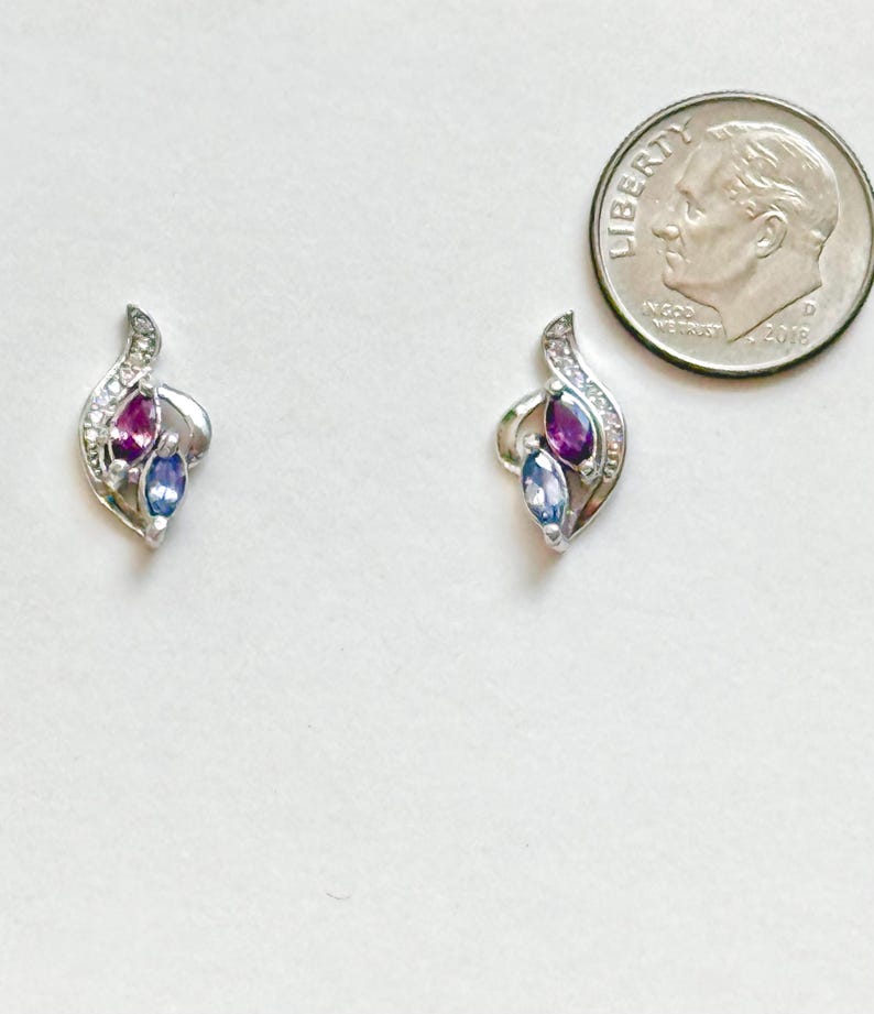 Peut inclure: Une paire de boucles d'oreilles argent&eacute;es au design incurv&eacute; avec de petites pierres claires, chacune sertie d'une pierre violette et d'une pierre bleue taille marquise, pr&eacute;sent&eacute;es &agrave; c&ocirc;t&eacute; d'une pi&egrave;ce de 17,9 mm pour montrer leur petite taille.