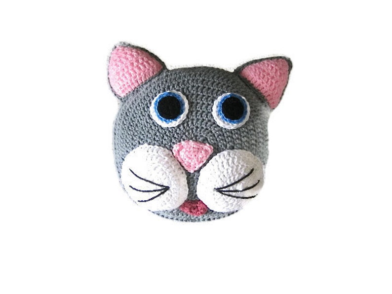 Op de afbeelding: Een grijs gehaakt kattenhoofd met roze oren, witte snorharen en blauwe ogen.
