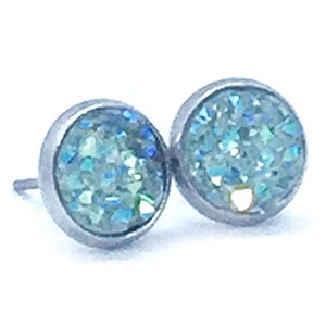 May include: A pair of silver stud earrings with light blue glitter embedded in the round stones.