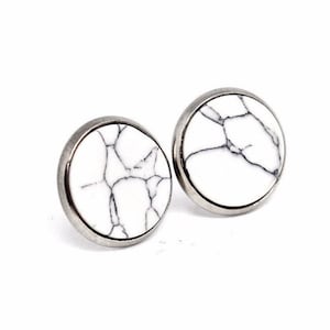 May include: A pair of white marble stud earrings with silver settings. The marble has a natural veining pattern.