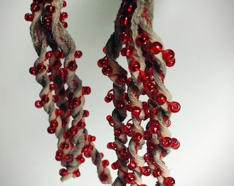 Cream leather earrings decorated with bright red glass beads