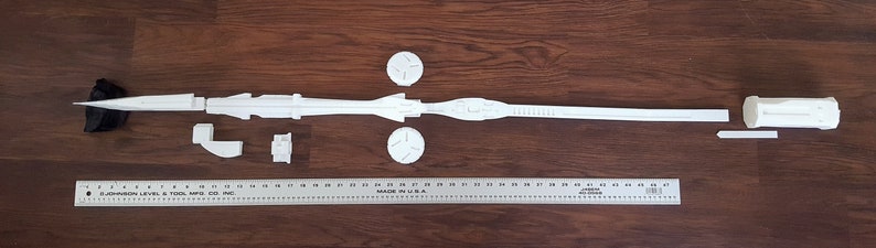 Puede incluir: Un modelo de nave espacial de pl&aacute;stico blanco, desmontado en varias piezas. Las piezas incluyen el cuerpo principal, dos alas, un cono de nariz y una peque&ntilde;a pieza cil&iacute;ndrica. El modelo est&aacute; dispuesto sobre una superficie de madera.