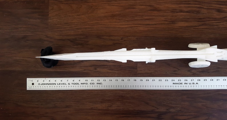 Puede incluir: Modelo de ca&ntilde;&oacute;n blanco de pl&aacute;stico sobre ruedas, que mide aproximadamente 69 cm de largo. El ca&ntilde;&oacute;n est&aacute; sobre una superficie de madera.