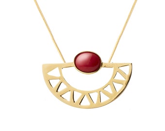 May include: A gold necklace with a red gemstone pendant. The pendant is a half-circle design with a geometric pattern.