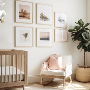 May include: A white rocking chair with a pink pillow in a nursery with a crib, a plant in a woven basket, and framed artwork on the walls.