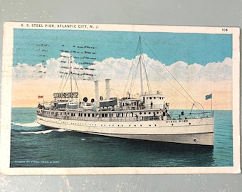 May include: A vintage postcard featuring a white steamboat named "Steel Pier" sailing on a blue body of water. The postcard is titled "S.S. Steel Pier, Atlantic City, N.J." and has the number "106" in the top right corner. The postcard is faded and has a vintage look.