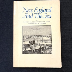 Könnte beinhalten: Ein Vintage-Buch mit dem Titel "New England And The Sea" mit cremefarbenem Einband. Der Titel ist in blauer Schrift gehalten, darunter die Namen der Autoren. Auf dem Cover befindet sich eine Schwarz-Weiß-Illustration einer Hafenszene.