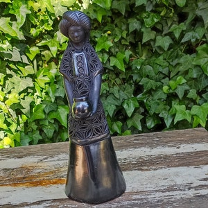 Jovem mulher segurando um pote de barro preto, decoração para casa, impressionante estatueta de barro negro, cerâmica mexicana feita à mão em San Bartolo, perto de Oaxaca, México