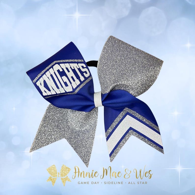 May include: A cheerleading bow with a blue and silver glitter design. The bow features the word "KNIGHTS" in white on a blue ribbon. The bow has a white center and a silver glitter accent. The bow is designed for game day.