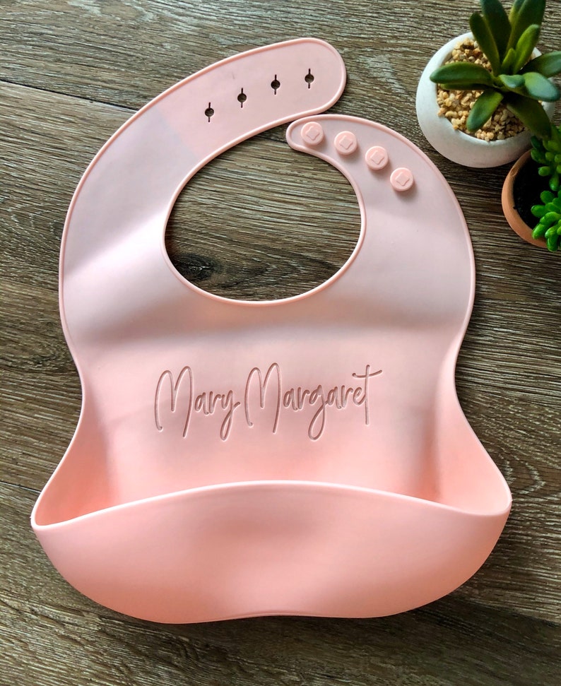 Custom Pink Baby Bib with Baby's name laser engraved onto center on wooden background