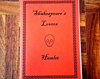 May include: A red book cover with the title "Shakespeare's Lovers" and the word "Hamlet" in black script. A skull graphic is centered between the title and the word "Hamlet". The cover has a decorative black border.
