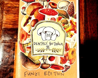 May include: A notebook with a collage of mushroom illustrations. The cover features a central label with mushroom graphics and the text "Deathly Botanica III" and "Fungi Edition". The background is a light brown color.
