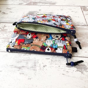 May include: A double zippered pouch with a colorful print of cartoon dogs. The pouch is made of fabric and has a green lining.