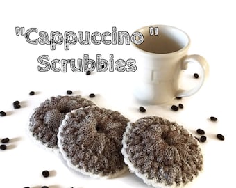 May include: Three brown and white crocheted scrubbies, resembling coffee beans, with the text "Cappuccino" Scrubbie's" on a white background with coffee beans scattered around.