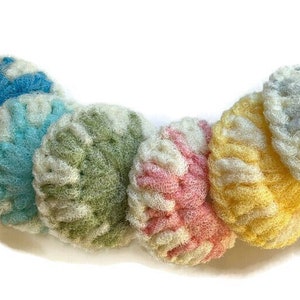 May include: Six colorful crocheted scrubbies in shades of blue, green, pink, and yellow. The scrubbies are made of a soft, textured material and are perfect for cleaning dishes or other surfaces.