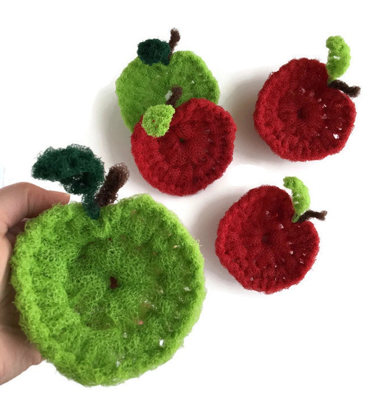 Puede incluir: Cuatro manzanas de crochet, dos rojas y dos verdes, con hojas y tallos verdes. Las manzanas est&aacute;n hechas con un hilo texturizado y tienen una superficie ligeramente rugosa.