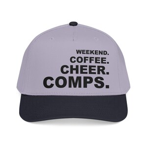 Peut inclure: Casquette de baseball avec une couronne violet clair et une visière bleu marine. Le texte "WEEKEND. COFFEE. CHEER. COMPS." est imprimé en noir sur le devant, idéal pour un look décontracté.