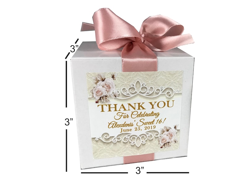 Op de afbeelding: Witte bedankbox met een roze satijnen lint en strik. De doos heeft een decoratief label met een bloemenontwerp en de tekst "THANK YOU For Celebrating Alexdents' Sweet 16! June 25, 2019". De doos meet 7,6 cm bij 7,6 cm bij 7,6 cm.