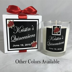 May include: A white box with a red ribbon tied around it. The box has a black and white label with red roses and the text "Kristin's Quincea&ntilde;era June 19, 2018". A clear glass candle jar with a black and white label with red roses and the text "Kristin's Quincea&ntilde;era June 19, 2018". The text "Other Colors Available" is printed below the image.