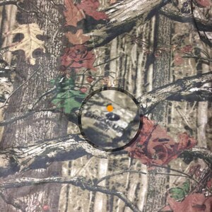 May include: Camouflage fabric with a brown, green, and red pattern. The fabric has a circular logo with the text "Break Up Infinity" in the center.