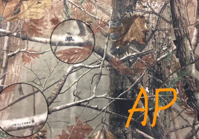 May include: Camouflage fabric with the text " Realtree" and "30" printed on it. The fabric has a brown, green, and tan color scheme.