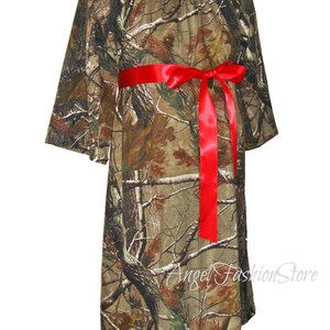 May include: A camouflage print maternity dress with a red ribbon tied at the waist. The dress has a loose, flowing fit and is perfect for a casual, comfortable look.