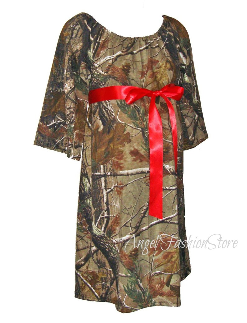 May include: A camouflage print maternity dress with a red ribbon tied at the waist. The dress has a loose, flowing fit and is perfect for a casual, comfortable look.