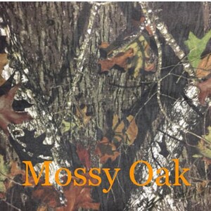 May include: A close-up of a camouflage fabric with a brown, green, and white pattern. The fabric has the words "Mossy Oak" printed on it.
