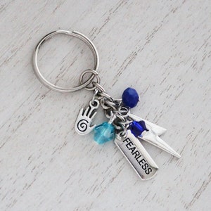 May include: A silver keychain with a silver charm that says "FEARLESS" and several blue and turquoise beads.
