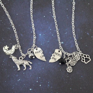 May include: Two silver-toned necklaces with various charms. One features a howling wolf, moon, and star. The other has a motorcycle, paw print, and a broken heart charm with the text "PART I CRIME" and "NERS IN IME".