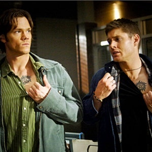 K&ouml;nnte beinhalten: Zwei M&auml;nner in blauen Jeansjacken, einer mit einem gr&uuml;n gestreiften Hemd und der andere mit einem schwarzen Hemd, beide mit einem Tattoo eines Symbols auf der Brust.