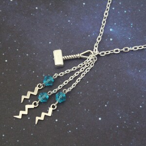 May include: Silver necklace with a silver hammer charm and three dangling blue crystal beads with silver lightning bolt charms.