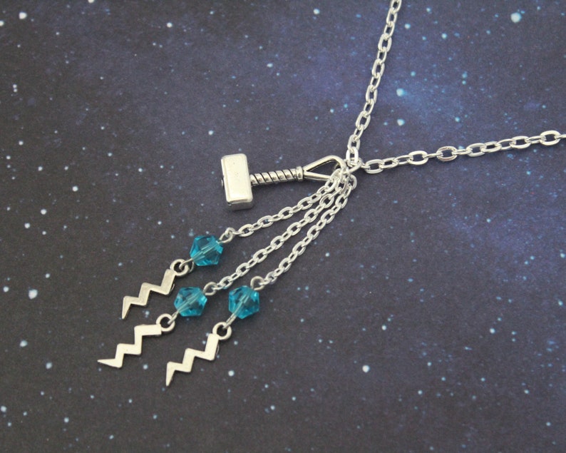 May include: Silver necklace with a silver hammer charm and three dangling blue crystal beads with silver lightning bolt charms.
