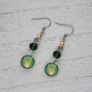 以下が含まれることがあります： 緑と黄色のデザイン、シルバー仕上げ、緑と金のビーズアクセント、シルバーフックが特徴のぶら下がりピアス。ピアスには円形のペンダントが付いています。