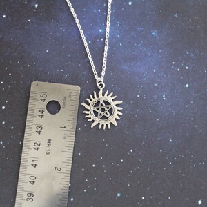 K&ouml;nnte beinhalten: Silberne Halskette mit einem Pentagramm-Anh&auml;nger in einem Sonnensymbol. Der Anh&auml;nger hat einen Durchmesser von etwa 2,5 cm.