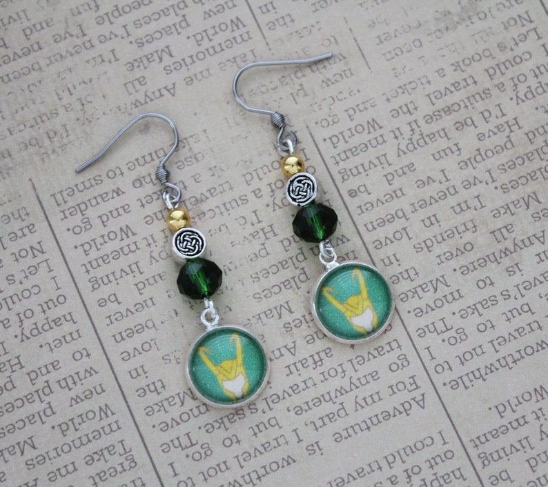 以下が含まれることがあります： シルバーカラーのぶら下がりピアス。緑とゴールドのアクセントが特徴です。各ピアスには、ターコイズ色の背景に黄色のデザインが施された丸いチャーム、緑色のビーズ、ケルトノットのディテールが施されています。ユニークなアクセサリーです。