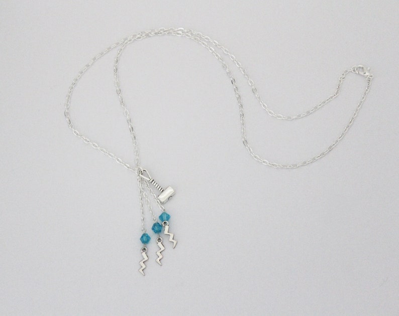 May include: Silver chain necklace with a silver hammer charm and three blue crystal beads hanging from it.